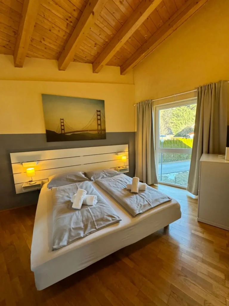 Gemütliches Schlafzimmer im schwedisch-österreichischen Stil mit Doppelbett und Blick nach draußen.