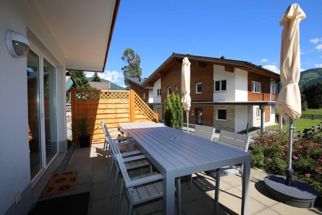 Charmante Terrasse mit Tisch, Stühlen und Blick auf Ferienwohnungen in Zell am See.